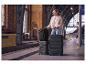 Femme avec des bagages noirs et un sac à dos dans une gare.