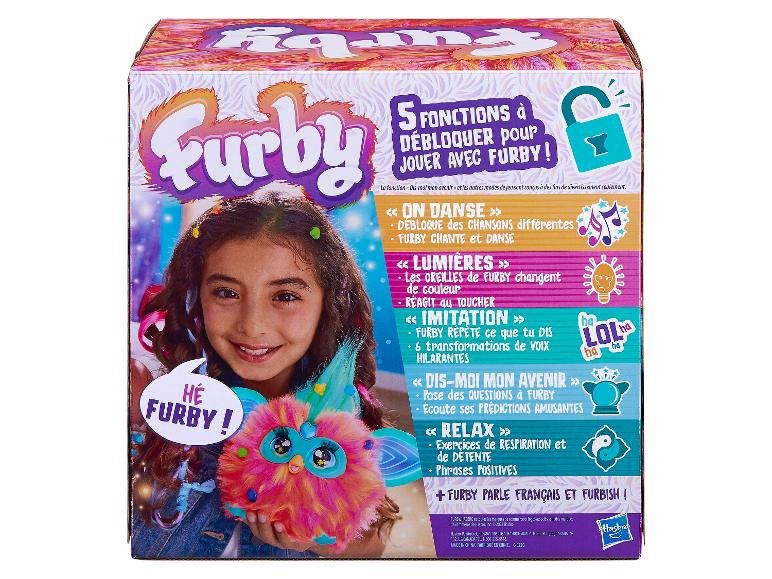 Un jouet Furby rose que tient un enfant. La boîte présente différentes options de jeu.