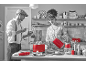 Un couple dans une cuisine avec de petits appareils rouges : grille-pain, bouilloire et mixeur.