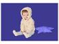 Bébé heureux en veste polaire à capuche couleur crème et legging gris, assis à côté d'un oreiller étoile violet.
