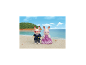 Deux figurines de lapins, l'une en costume de marin et l'autre en robe violette, sur une plage de sable.