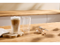 Verre de latte macchiato, verre vide et biscuits sur une table en bois.