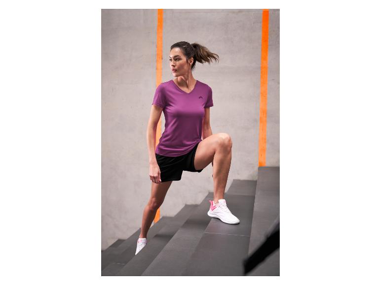 Femme en t-shirt de sport violet et short noir faisant de l'exercice dans les escaliers.