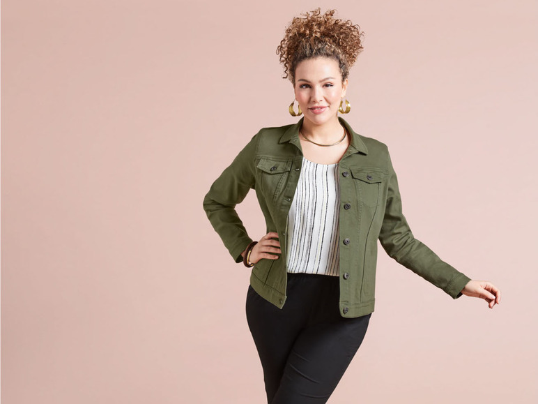 Une femme porte une veste en jean verte, un haut rayé et un pantalon noir.