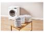 Machine à laver avec sacs à linge remplis de vêtements sur une étagère en bois.