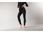 Une femme portant des sous-vêtements thermiques noirs, comprenant un haut à manches longues et un legging
