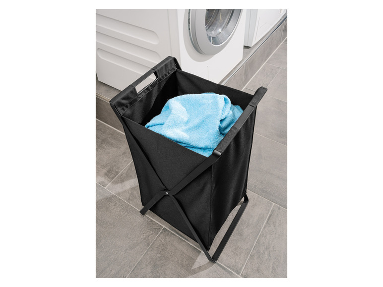 Un panier à linge noir avec une serviette bleue dans la salle de bain.