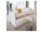 Lit bébé blanc avec un oreiller lion jaune et un oreiller étoile bleu clair dans une chambre d'enfant.