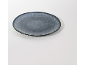 Assiette ovale en céramique gris foncé avec des bords mouchetés plus clairs, sur fond blanc.
