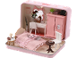 Une chambre de poupée miniature rose avec un lit, un bureau, une armoire et une petite table.