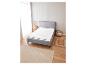 Un cadre de lit gris avec un matelas blanc et un sol en bois beige.