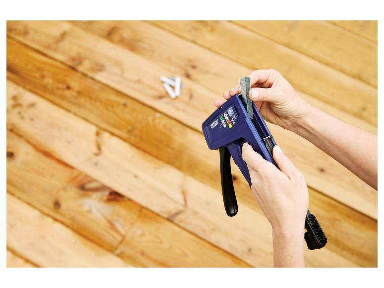 Personne chargeant l'agrafeuse manuelle LIVARNO® Handtacker »RPC7« avec des agrafes sur fond en bois.