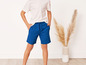 Un enfant porte un t-shirt blanc et un short bleu.