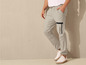 Un homme portant un pantalon de survêtement gris clair avec des accents noirs.