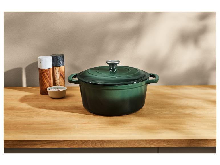 Cocotte en fonte verte sur un comptoir en bois.