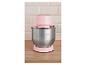 Robot de cuisine rose avec bol en acier inoxydable sur une surface en bois.
