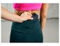 Une femme portant un legging vert avec un smartphone dans la poche.