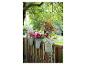 Jardinières avec pétunias et fuchsias suspendues à une clôture en bois.