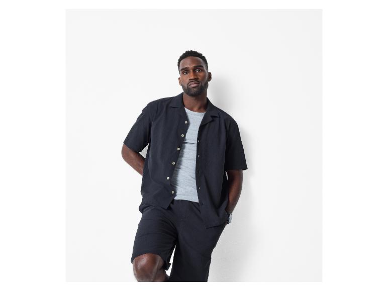 Homme en chemise et short noirs, avec un t-shirt gris.