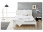 Lit blanc avec couette et oreillers, lampadaire, tapis et table d'appoint dans une chambre moderne.
