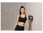 Une femme en soutien-gorge de sport noir et leggings avec un rouleau en mousse