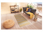 Un tapis d'extérieur rayé sur une terrasse en bois avec un canapé, des coussins et un pouf rond.
