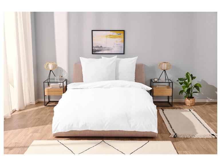 Draps blancs, tables de chevet et tapis minimalistes dans une chambre à coucher.