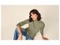 Femme en pull côtelé olive et jean bleu, assise par terre.