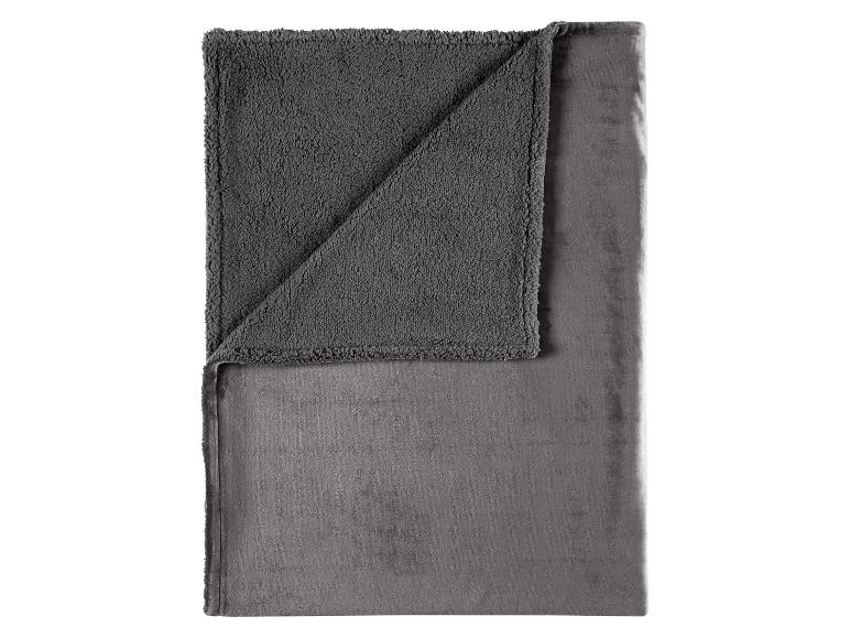 Couverture grise avec deux textures différentes, pliée et vue de dessus.