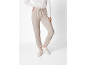 Femme en pantalon de jogging beige et pull blanc, avec des baskets claires.