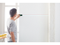 Homme utilisant un niveau laser pour projeter une ligne rouge sur un mur blanc