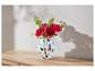 Un vase avec des pivoines rouges sur une table en bois.