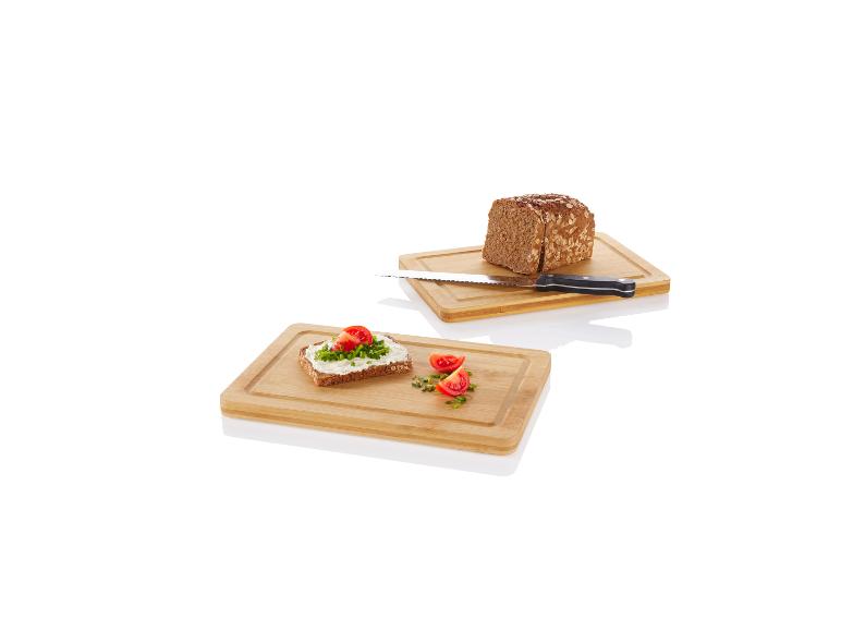 Deux planches à découper en bois avec un pain, un couteau et des tomates.