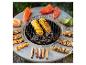 Barbecue rond avec maïs, poivrons, saumon, brochettes de crevettes et saucisses.