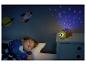 Un enfant dort dans un lit avec un projecteur de veilleuse tortue projetant des étoiles et des lunes.