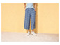 Une femme portant un pantalon bleu à fleurs et des baskets blanches.