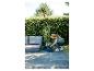 Femme plantant des fleurs en pots sur une terrasse avec mobilier de jardin.