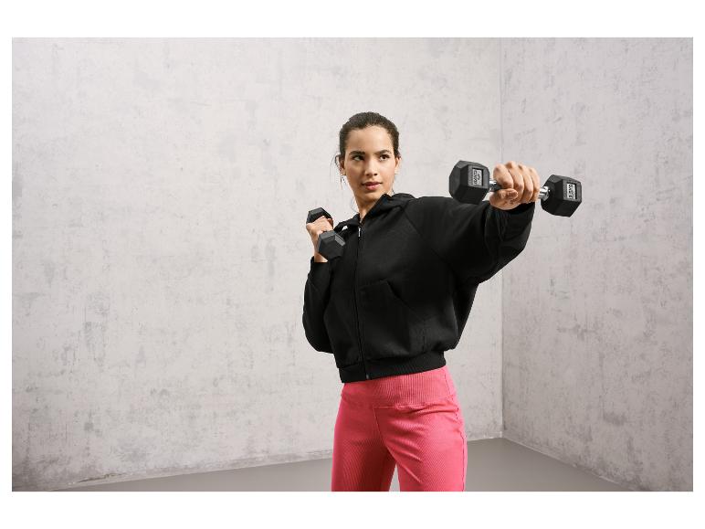 Une femme en sweat-shirt noir et leggings roses s'entraîne avec des haltères.