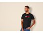 Homme en t-shirt de Noël noir avec des bonnets de Père Noël, posant sur fond clair