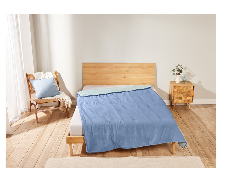 Un lit avec une couette bleue dans une chambre à coucher