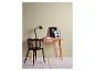 Un bureau en bois moderne avec une chaise noire, une lampe de bureau noire et deux tableaux encadrés.