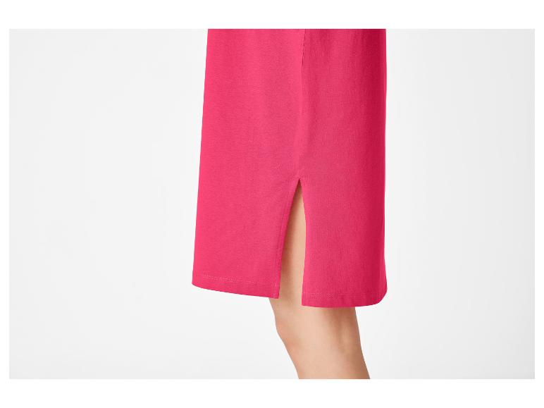Détail d'une jupe fuchsia avec une fente latérale, montrant une partie de la jambe.