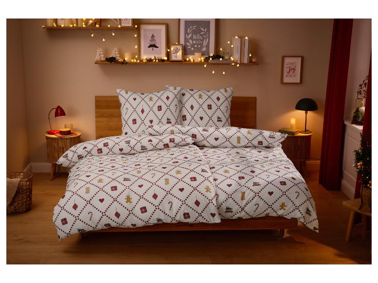 Chambre décorée pour Noël avec une parure de lit à motifs festifs et des lumières.