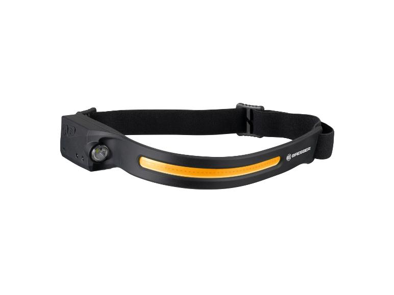 Une lampe frontale Bresser noire avec une bande lumineuse orange.