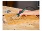Une personne utilise un outil de pyrogravure Parkside pour décorer une planche en bois.