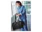 Une femme portant une veste en jean inspecte un sac de voyage noir.