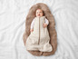 Un bébé dans un sac de couchage rayé sur une couverture tricotée.