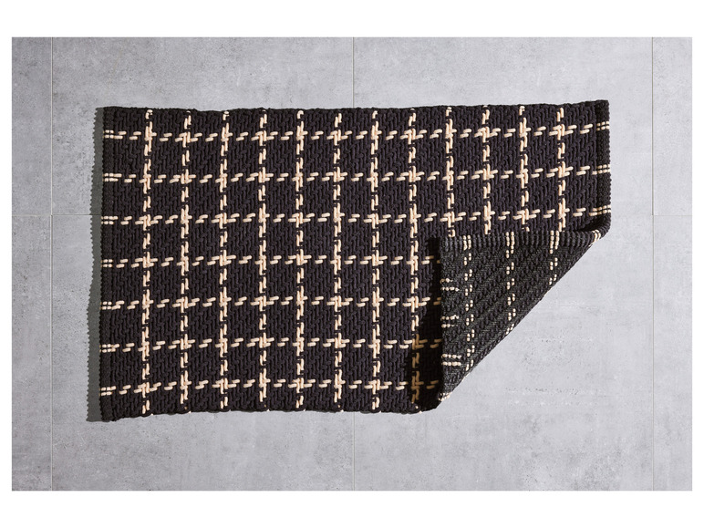 Un tapis à rayures blanches et noires avec un motif géométrique.