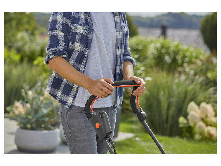 Un homme utilise une tondeuse à gazon dans un jardin.