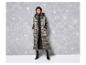 Une femme porte un long manteau d'hiver gris et des bottes noires.